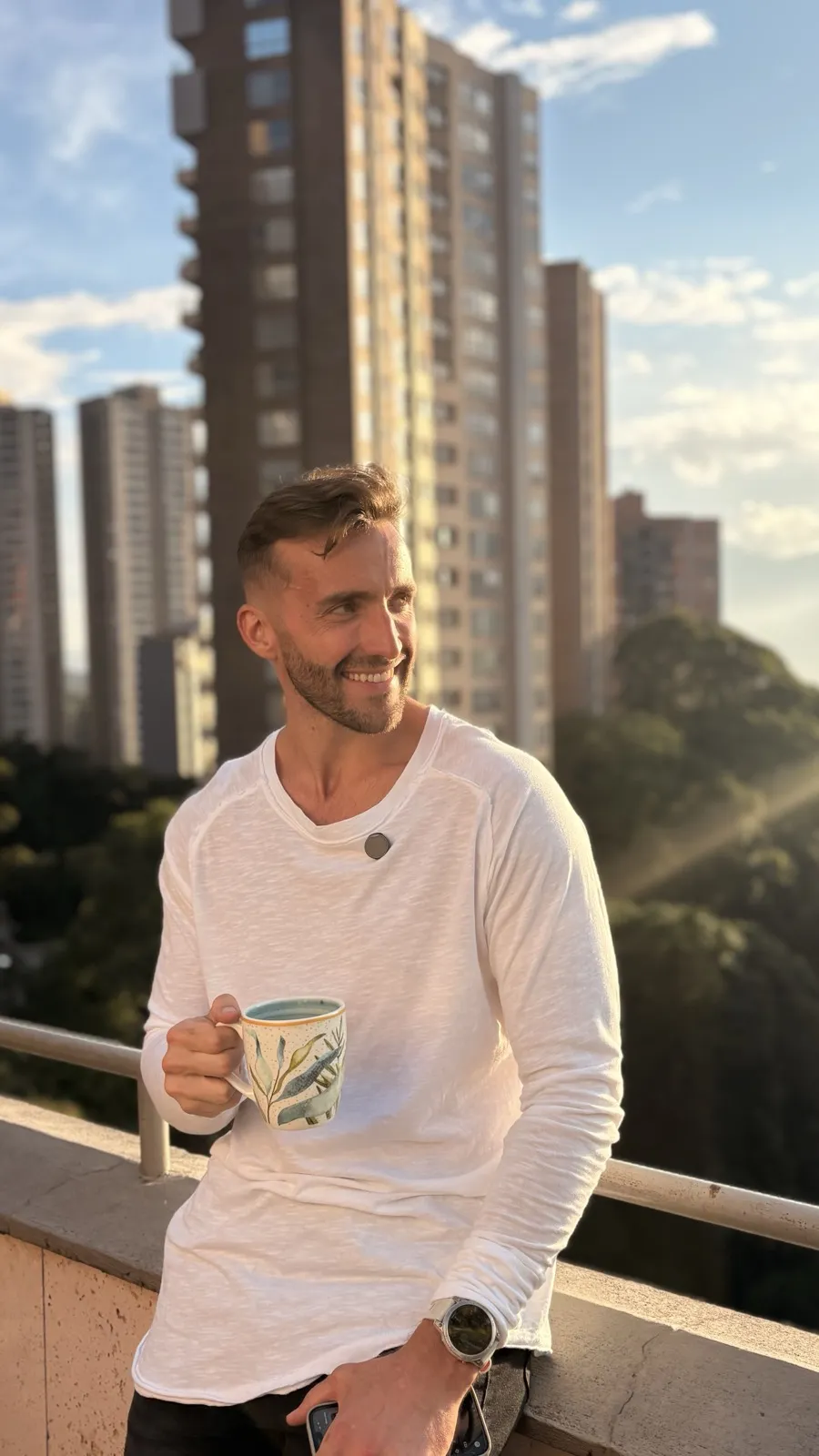 Ethan on a rooftop at golden hour, city skyline behind
